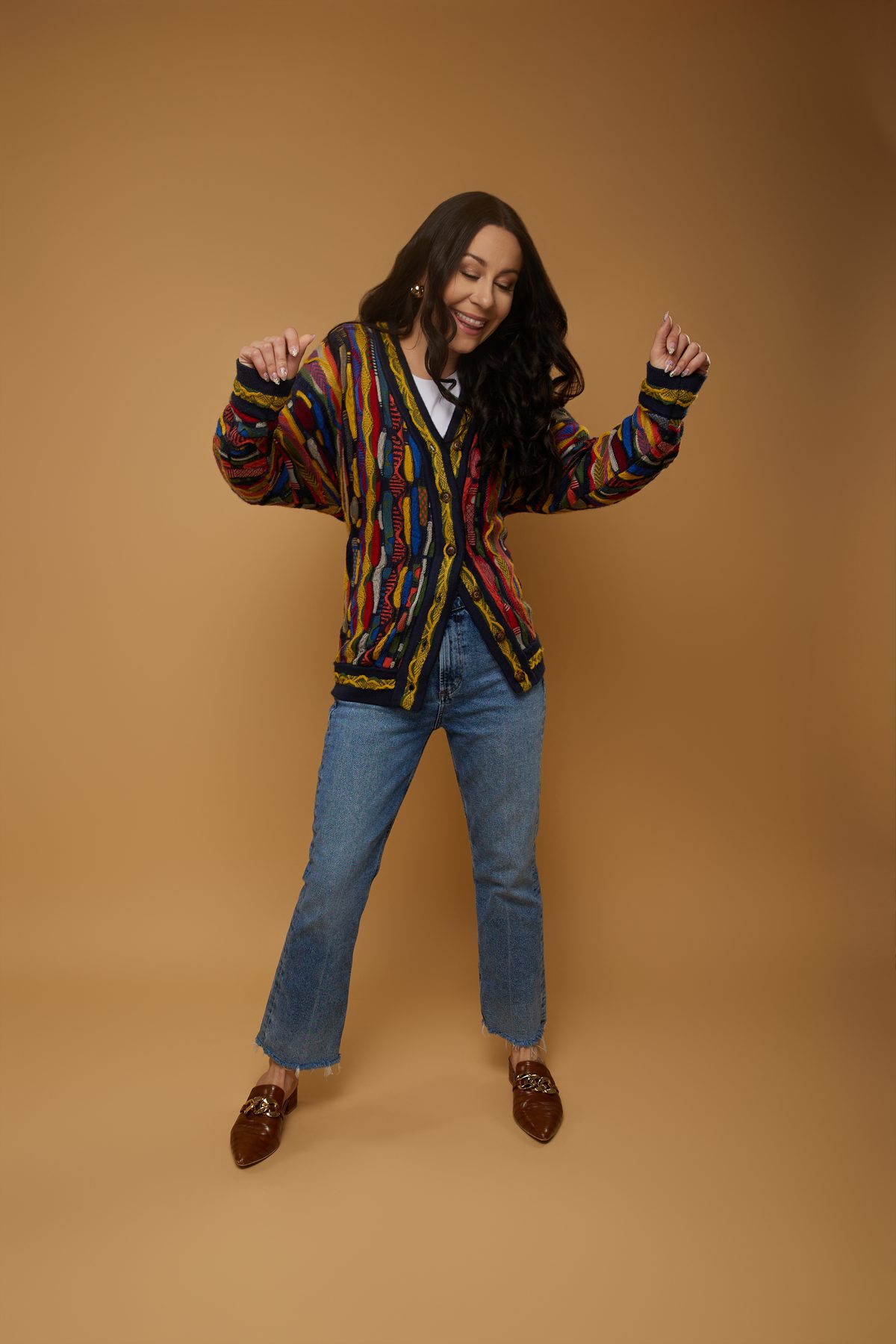 Bryanna Baptiste dancing in her Coogi cardigan against a caramel backdrop